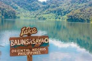 Balinsasayao Lake with lush green surroundings and calm water