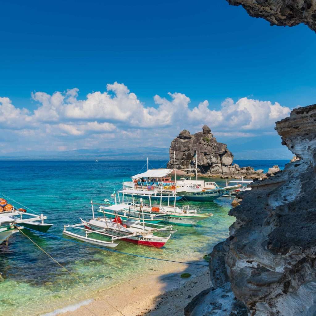 Scenic view of Apo Island day tour with white sand and rock formations.