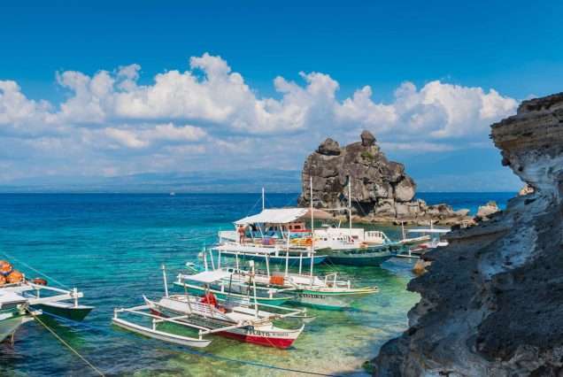Scenic view of Apo Island day tour with white sand and rock formations.